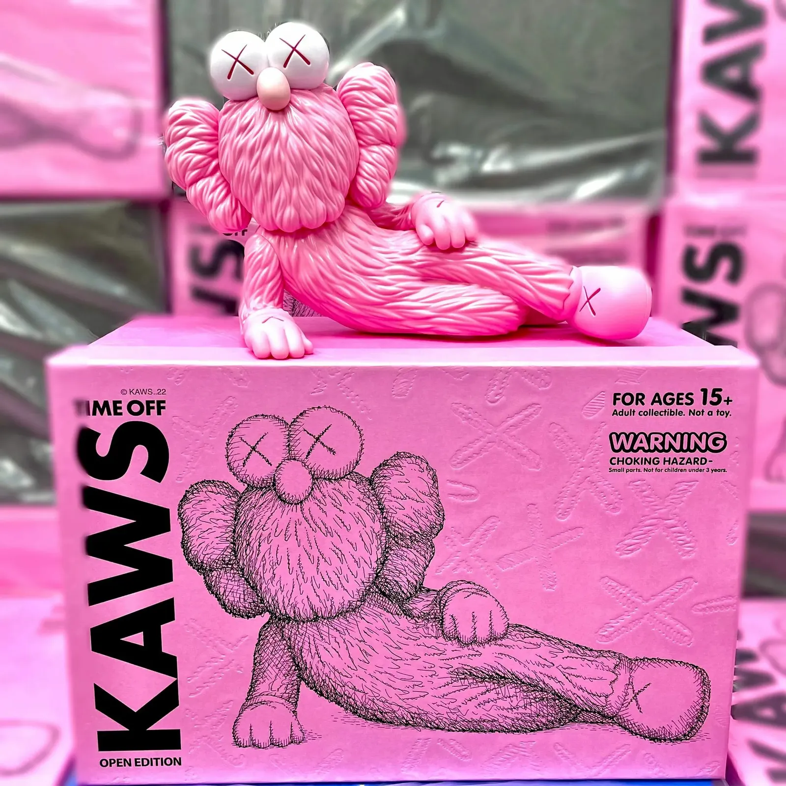 Figura Kaws Time Off Rose, personaje Kaws estilizado sentado, caja abierta, aproximadamente 28 cm de altura.