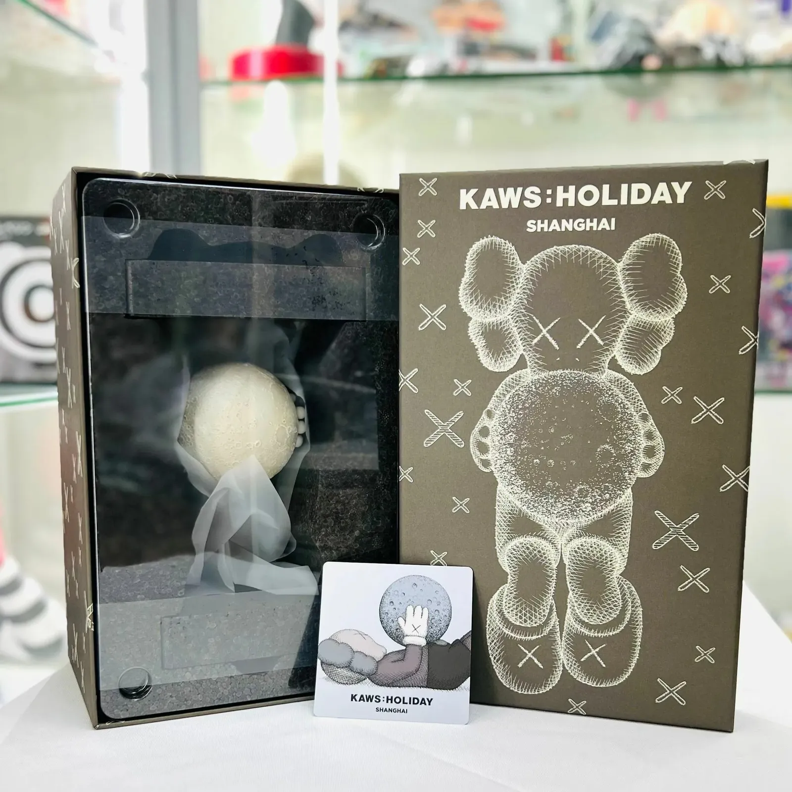 Figura Kaws:Holiday Shanghai marrón de vinilo, personaje reclinado de Kaws con luna fluorescente, 24 cm de largo.