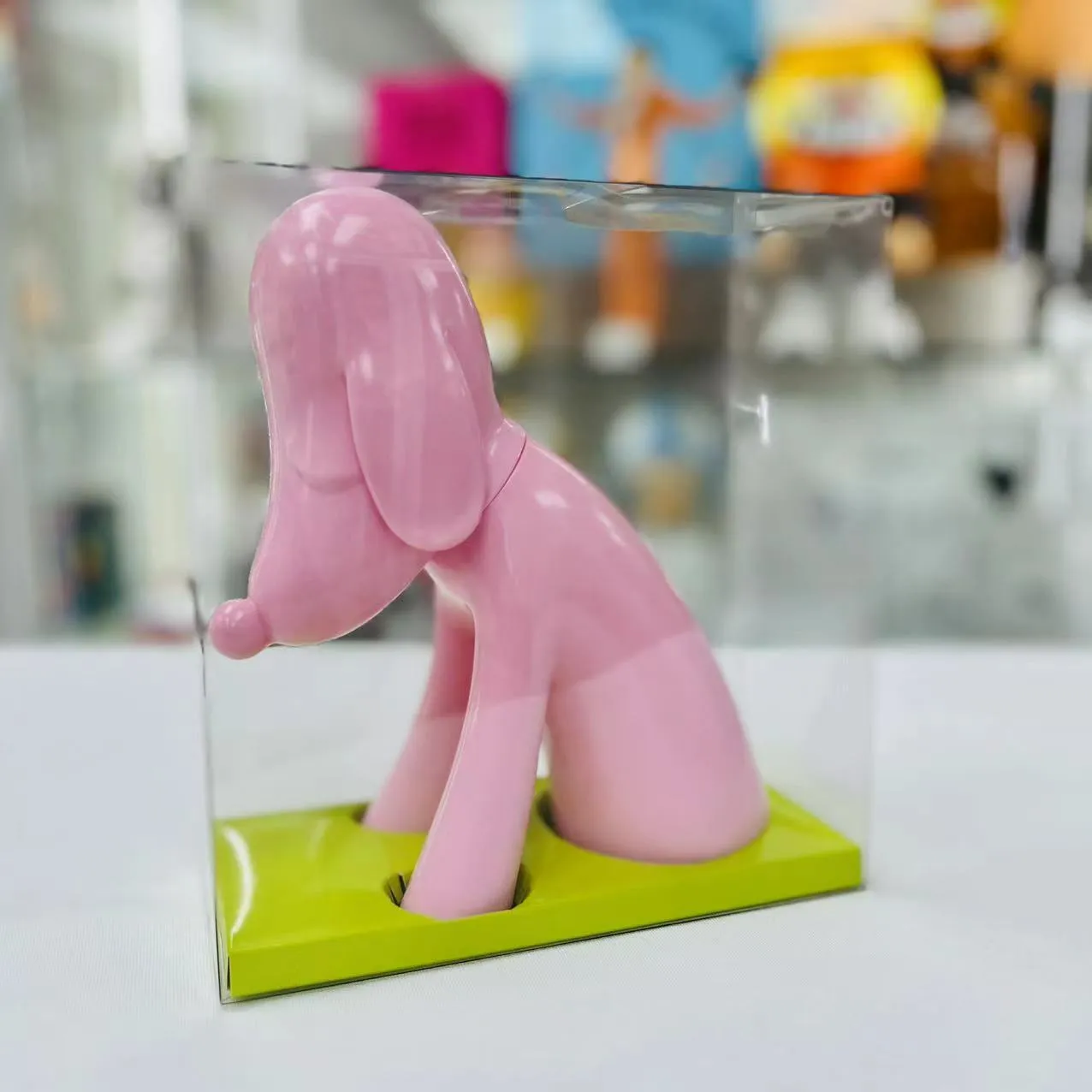 Hucha de perro estilizada en color rosa, dispuesta sobre una superficie neutra, mostrando sus formas escultóricas suaves y