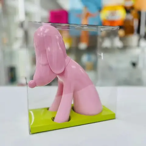 Hucha de perro estilizada en color rosa, dispuesta sobre una superficie neutra, mostrando sus formas escultóricas suaves y