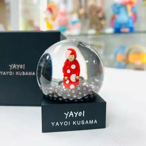 Bola de nieve de Yayoi Kusama con el motivo 'YAYOI', mostrando puntos de colores y elementos artísticos en su interior.