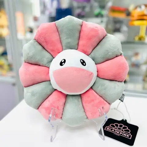 Cojín Flor Blackpink + Takashi Murakami, 30cm de diámetro, colores rosa y gris, colocado sobre una superficie.