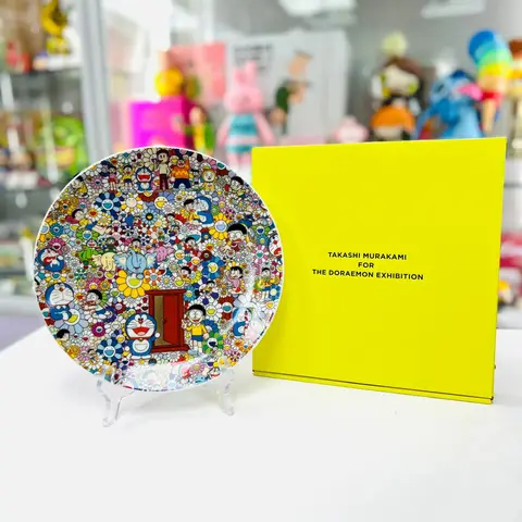 Plato de cerámica con motivos florales de Takashi Murakami y el personaje Doraemon, sobre fondo blanco.