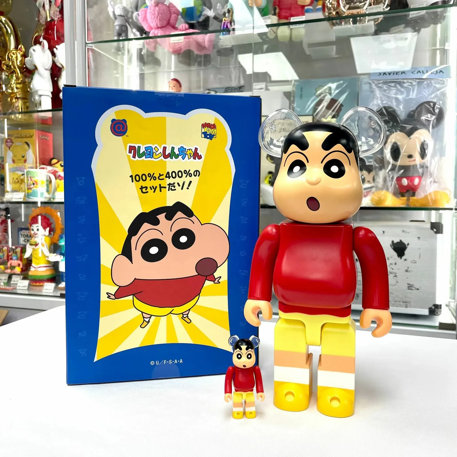 Deux figurines BE@RBRICK Shin-chan, une petite (100%) et une grande (400%), posées ensemble.