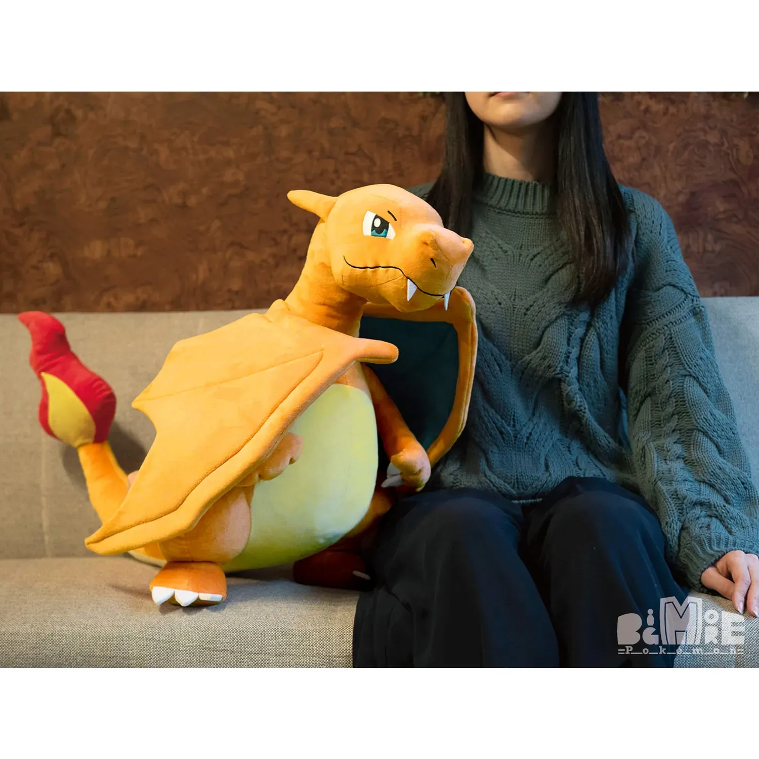 Grande peluche Pokémon Dracaufeu, couleur orange vif, ailes bleues et ventre crème, avec une expression amicale.